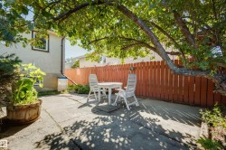 Concrete patio area with a privacy fence and mature tree providing canopy - 