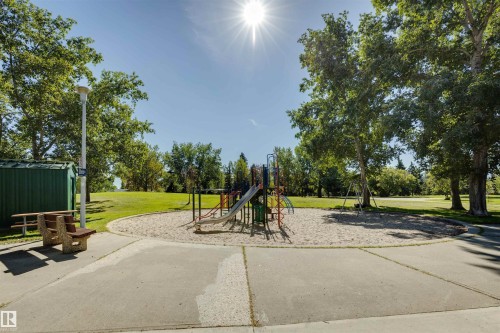 Community playground area featuring a sand base, children's play equipment, and mature trees - 10916 151 Street Nw, Edmonton, AB 
