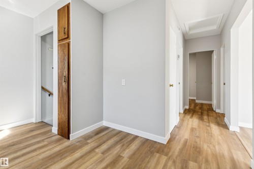 Wood-finish flooring throughout, light gray wall finishes, recessed ceiling detail, and built-in wood cabinetry - 10916 151 Street Nw, Edmonton, AB 