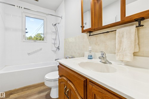 White bathtub with a shower kit, a grab bar, and a window - 10916 151 Street Nw, Edmonton, AB 