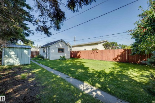Expansive backyard featuring a manicured lawn, a detached garage, and a garden shed - 10916 151 Street Nw, Edmonton, AB 