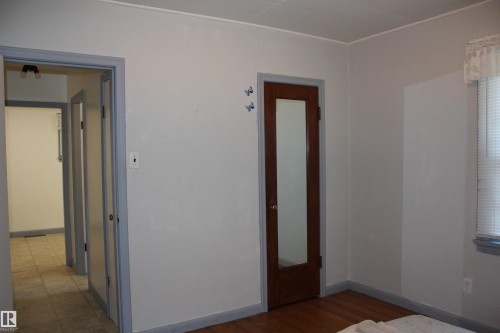 Hardwood flooring, light gray wall color, brown wood-finish door with full-length mirror, neutral tiled hallway flooring, white window blinds - 4406 49A Street, Vegreville, AB 