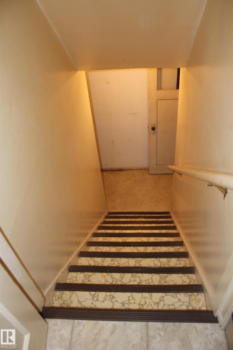 Stairwell with patterned stair treads and a handrail - 4406 49A Street, Vegreville, AB 