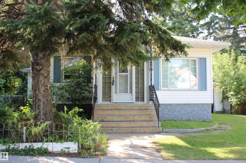 White siding exterior with blue shutters, a front entry with glass block sidelights, and a stone-patterned foundation - 4406 49A Street, Vegreville, AB 