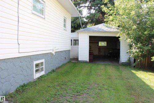 Detached garage with a shingled roof and an open entry, complemented by white siding on the main structure - 4406 49A Street, Vegreville, AB 