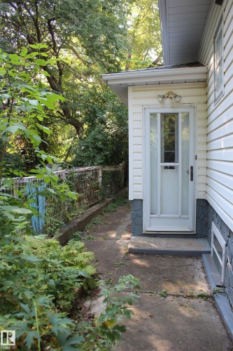 Entryway featuring a partially glass-paneled door, exterior wall sconce, and concrete walkway - 4406 49A Street, Vegreville, AB 