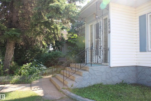 Front entrance featuring concrete steps, wrought iron railings, and a covered porch - 4406 49A Street, Vegreville, AB 