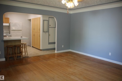 Wood-finish flooring throughout, light blue wall paint, white trim, and a ceiling fan with light fixture - 4406 49A Street, Vegreville, AB 