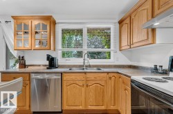 Kitchen featuring wood cabinetry, stainless steel dishwasher, double basin sink, and laminate countertops - 