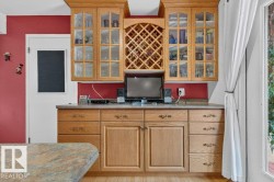 Wood-finish cabinetry with glass-front upper cabinets and an integrated wine rack - 