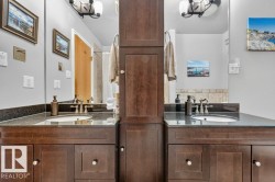 Dual vanity featuring dark wood cabinetry, integrated sinks, dark stone countertops, and individual mirrors - 