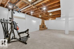 Spacious lower-level room featuring exposed wood ceiling joists with recessed lighting - 