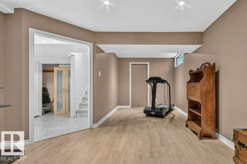 Finished lower level with wood-finish flooring, recessed lighting, a window, and a doorway leading to a tiled area with stairs - 11131 35A Avenue Nw, Edmonton, AB - Indoor