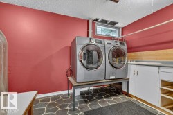 Dedicated laundry area featuring a window, built-in cabinetry, countertop space, and stone-patterned flooring - 