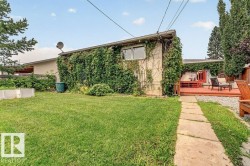 Expansive backyard featuring a green lawn, concrete stepping stone path, and a red-toned wood deck - 