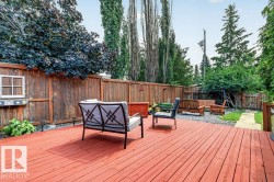 Expansive backyard featuring a large red-stained wood deck, perimeter wood fencing, and mature trees - 