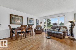 Expansive living area featuring wood-finish flooring, a bright picture window, and crisp white walls - 
