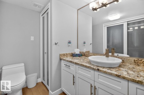Primary 2 piece Ensuite featuring White Cabinets, Granite Counters, and Storage. - #602 12303 Jasper Av Nw, Edmonton, AB 