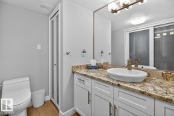Primary 2 piece Ensuite featuring White Cabinets, Granite Counters, and Storage. - 