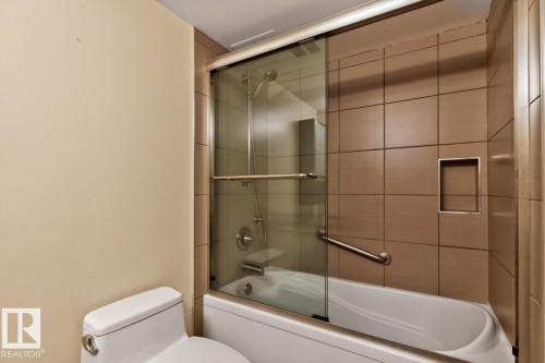 Soaker Tub w/ Shower featuring tiled walls, glass enclosure with sliding doors - #602 12303 Jasper Av Nw, Edmonton, AB 