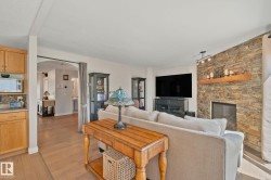 Living area featuring a stone accent wall, fireplace with a wood mantel, and wood-finish flooring - 