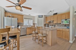 Kitchen featuring light wood cabinetry, stainless steel appliances, a center island with bar seating, and wood-finish flooring - 
