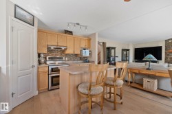Kitchen with wood-finish cabinetry, stainless steel double oven, and track lighting - 