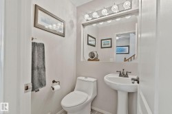Pedestal sink with a two-handle faucet, wall-mounted mirror, and vanity lighting fixture - 