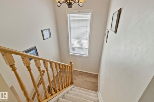 Staircase featuring a light wood railing and carpeted treads - 591 Byrne Crescent Sw, Edmonton, AB 