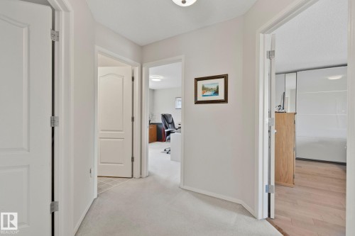 Hallway featuring light-toned carpeting and multiple doorways - 591 Byrne Crescent Sw, Edmonton, AB 