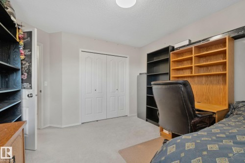 Neutral wall paint, white bi-fold closet doors, light-colored carpeting, and a flush-mount ceiling light fixture - 591 Byrne Crescent Sw, Edmonton, AB 
