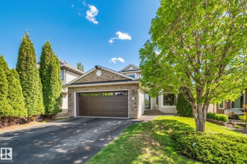 Brick facade with siding accents, attached garage, paved driveway, mature trees, and established landscaping - 591 Byrne Crescent Sw, Edmonton, AB 