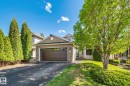Brick facade with siding accents, attached garage, paved driveway, mature trees, and established landscaping - 591 Byrne Crescent Sw, Edmonton, AB 