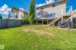 Expansive lawn area with a wooden fence and a multi-level deck featuring glass panel railings and stairs - 