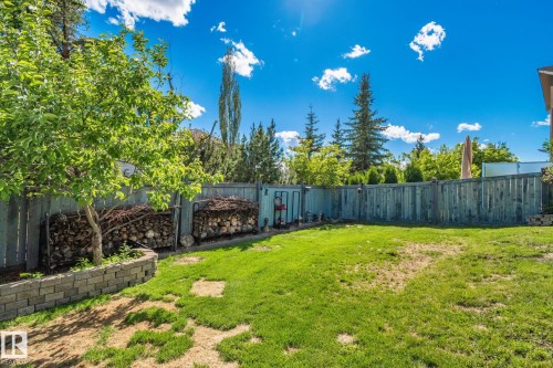 Expansive backyard featuring a partial grass lawn, mature trees, and a privacy fence - 591 Byrne Crescent Sw, Edmonton, AB 