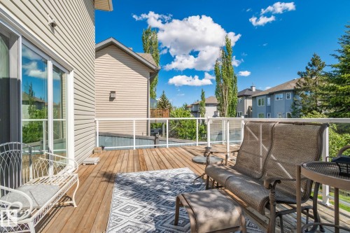 Deck with wood-finish flooring, glass panel railing, and sliding glass door access - 591 Byrne Crescent Sw, Edmonton, AB 