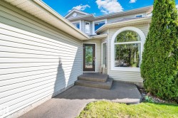 Light-toned siding exterior with a prominent arched window and a glass-paneled entry door - 