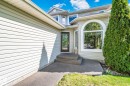 Light-toned siding exterior with a prominent arched window and a glass-paneled entry door - 591 Byrne Crescent Sw, Edmonton, AB 