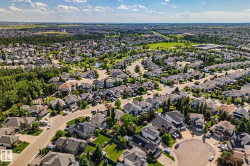 Residential community with varied architectural styles, mature trees, and a central green space with a pond - 591 Byrne Crescent Sw, Edmonton, AB 