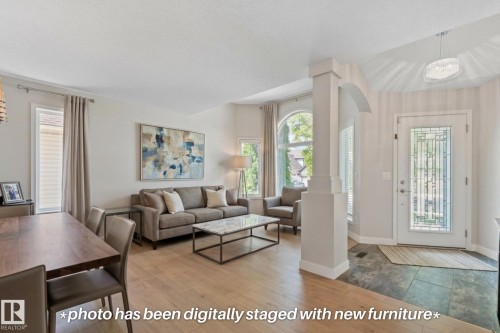 Hardwood-style flooring, arched entryway, decorative front door with transom window, recessed lighting, and large windows - 591 Byrne Crescent Sw, Edmonton, AB 