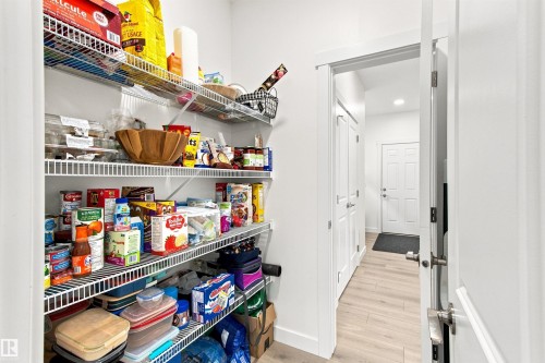 Well-appointed pantry featuring multiple wire shelving units, light wood-finish flooring, and recessed lighting - 107 Ellice Bend, Fort Saskatchewan, AB 