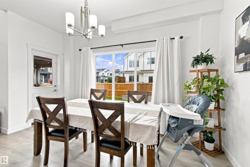 Dining area with wood-finish flooring, a contemporary chandelier, and a sliding glass door leading to the exterior - 107 Ellice Bend, Fort Saskatchewan, AB 