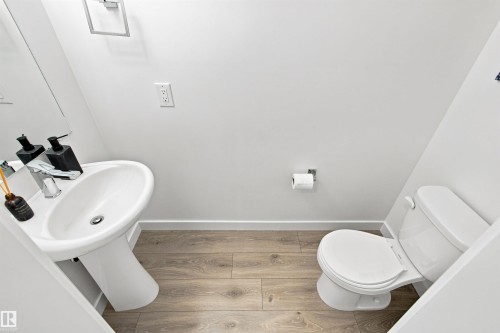 Pedestal sink with chrome faucet, wood-finish flooring, and a white toilet - 107 Ellice Bend, Fort Saskatchewan, AB 