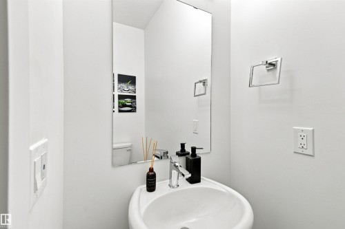 Modern powder room featuring a round vessel sink with polished chrome faucet, white quartz countertop, and large framed mirror - 107 Ellice Bend, Fort Saskatchewan, AB 