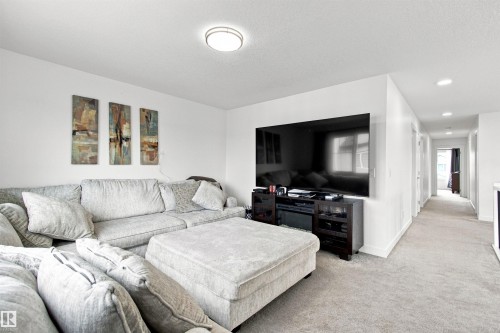 Wall-mounted television with media console, recessed lighting, and a neutral color palette - 107 Ellice Bend, Fort Saskatchewan, AB 