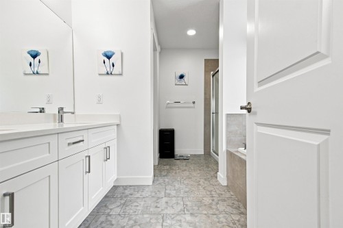 Dual sink vanity with white cabinetry, polished chrome fixtures, and a large wall mirror - 107 Ellice Bend, Fort Saskatchewan, AB 