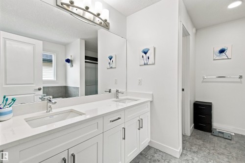 Dual vanity with white cabinetry, polished chrome fixtures, and a large integrated mirror - 107 Ellice Bend, Fort Saskatchewan, AB 