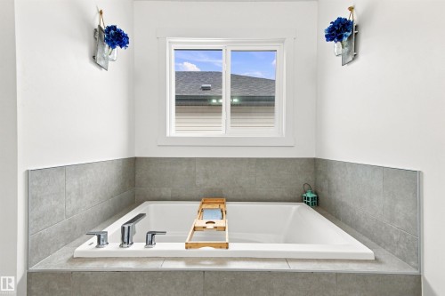 Built-in soaking tub with chrome fixtures, surrounded by grey tile - 107 Ellice Bend, Fort Saskatchewan, AB 