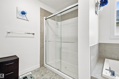 Shower enclosure with clear glass doors, chrome hardware, and a tile surround - 107 Ellice Bend, Fort Saskatchewan, AB 