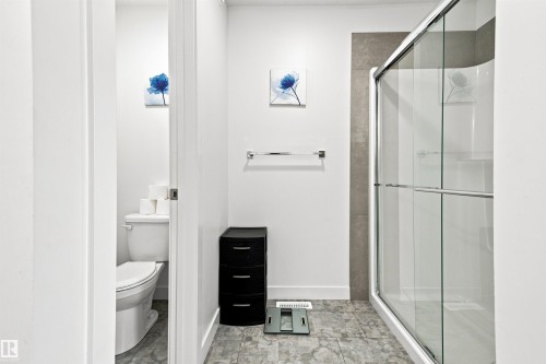 Walk-in shower with clear glass enclosure, white ceramic toilet, and tiled flooring - 107 Ellice Bend, Fort Saskatchewan, AB 